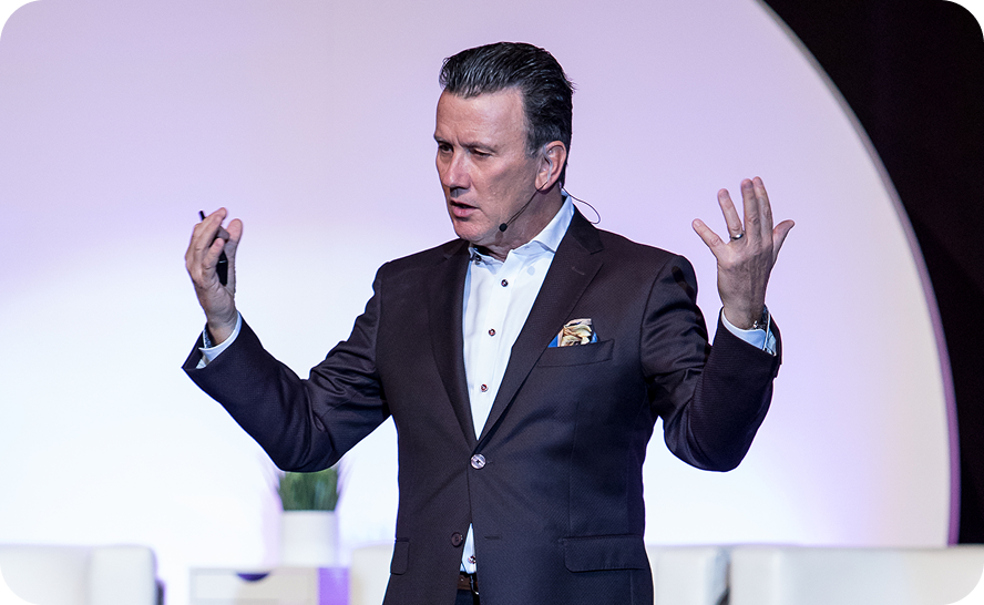 Man in dark suit giving an engaging presentation on stage