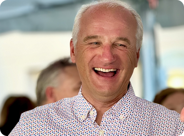 Smiling man in a patterned shirt enjoying a social event.